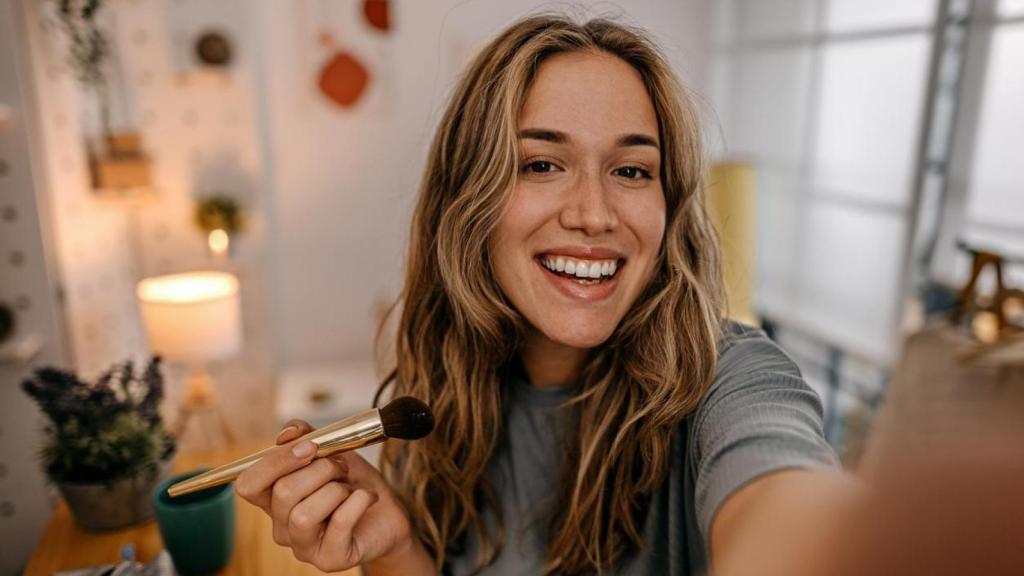 Mujer maquillándose frente al espejo.