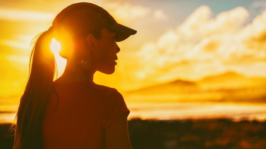 Mujer al atardecer con gorra.