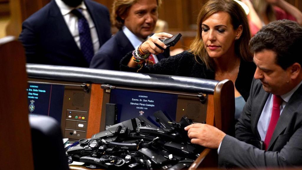 Varios diputados dejan los receptores en el escaño de Pedro Sánchez en señal de protesta.