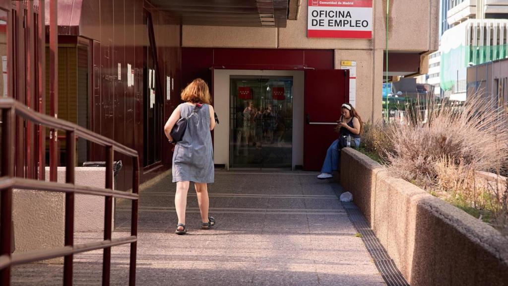 Una mujer frente a una oficina de empleo.