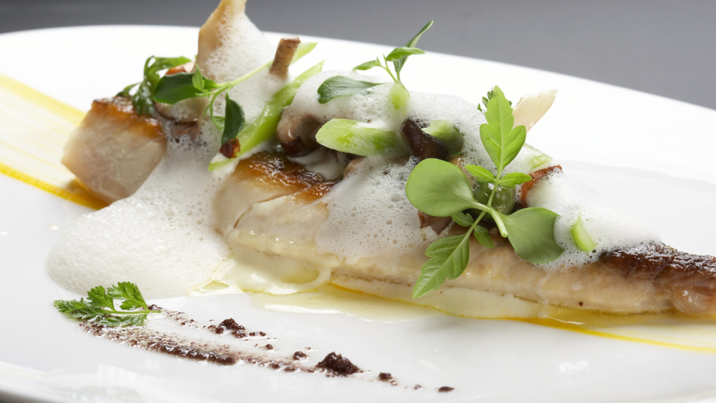 Lubina a la plancha con hojas verdes.