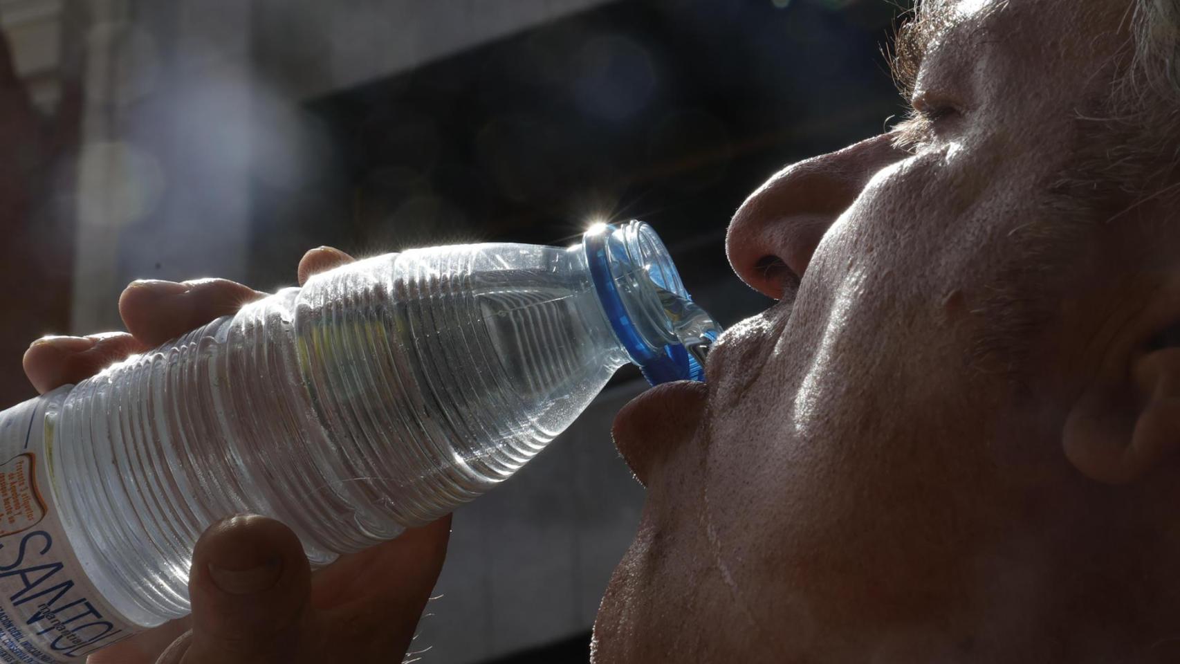 Un señor se refresca bebiendo una botella de agua.
