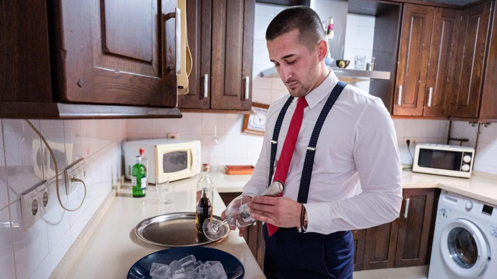 Cristian preparándole una copa a su madre en la cocina de su casa.