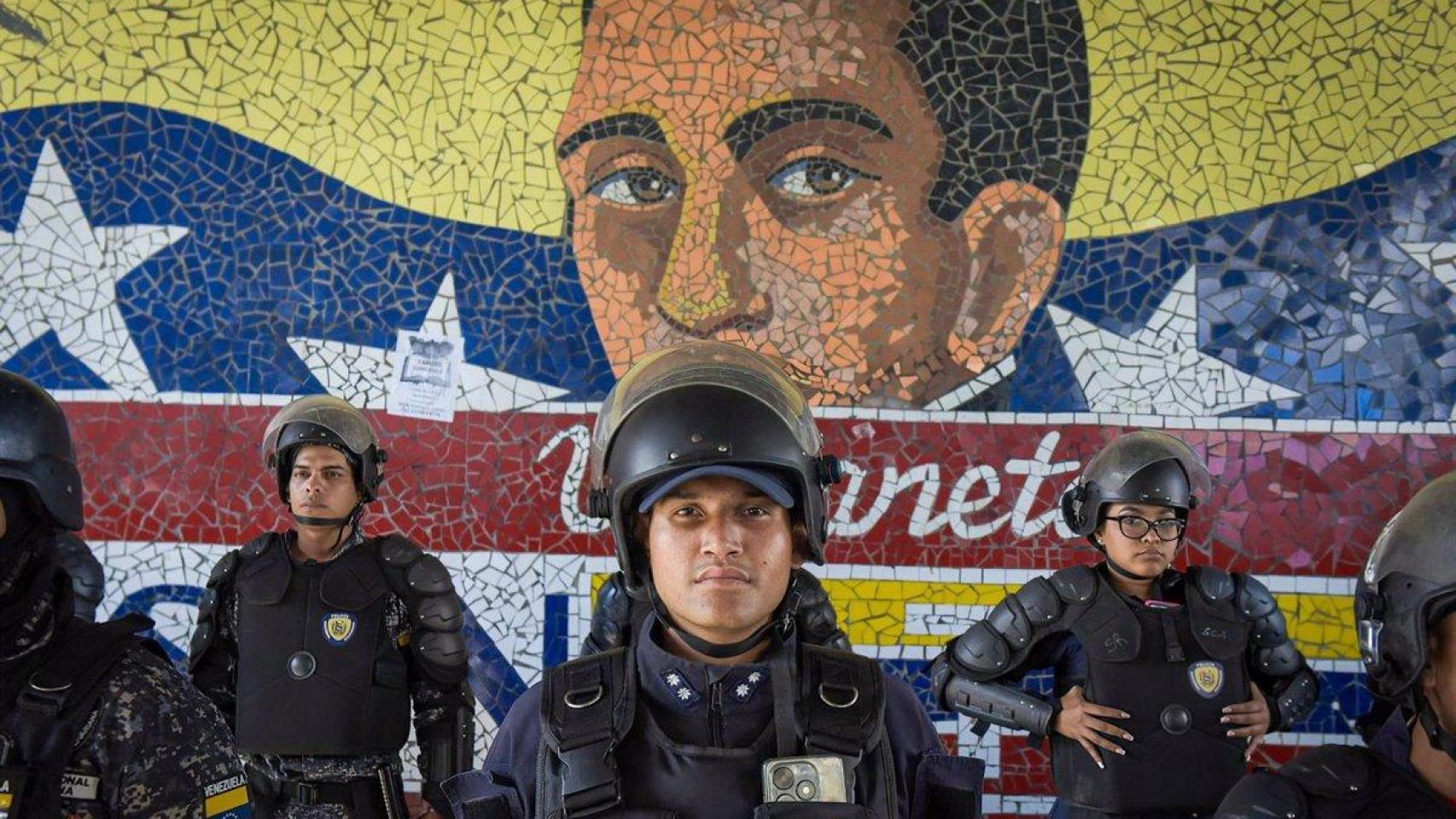 Miembros de seguridad de Venezuela portan sus armas con un mural de Simón Bolívar de fondo.