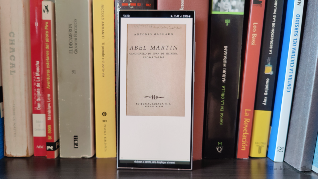 Libro electrónico en un móvil junto a varios libros en papel