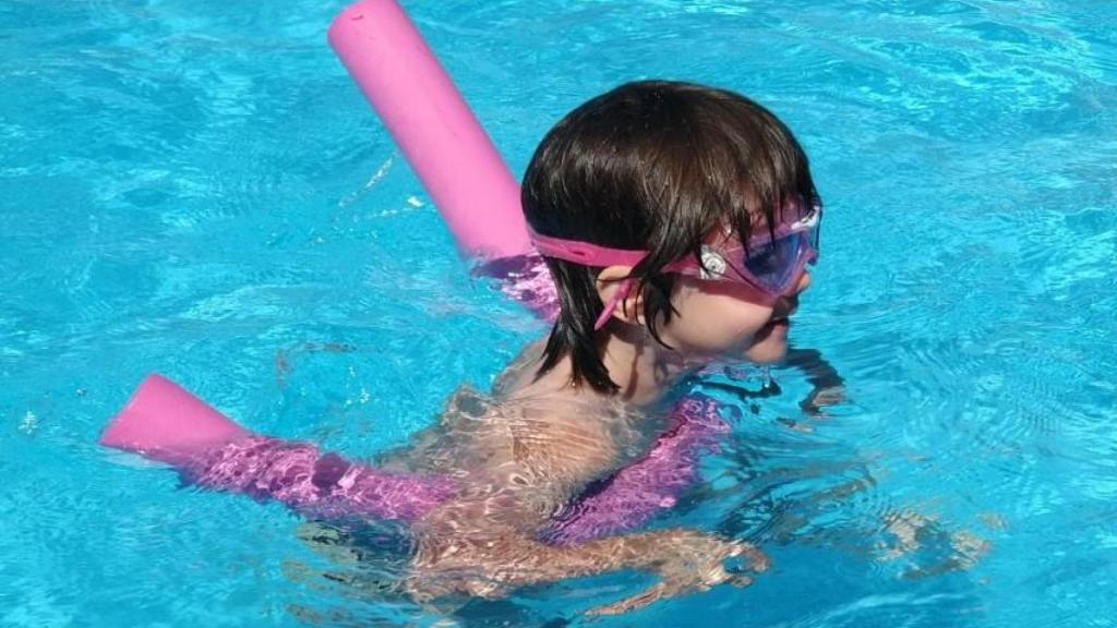 Una niña, con tubos para aprender a nadar.