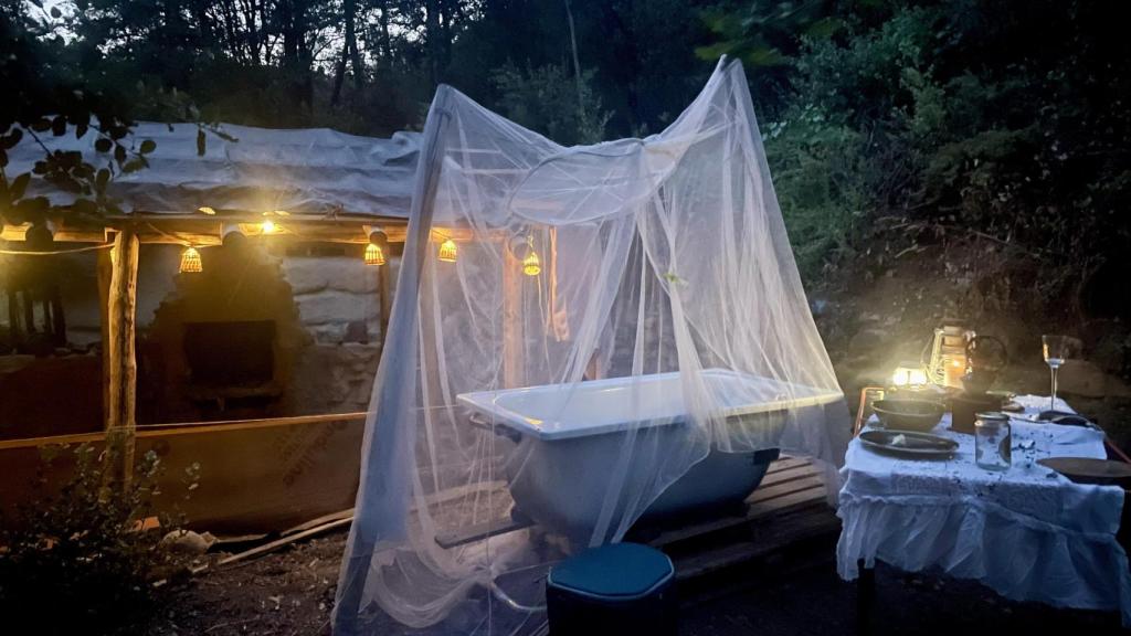 Una bañera con tul entre la cabaña  de Yayabushcraft y mesa puesta para cenar.