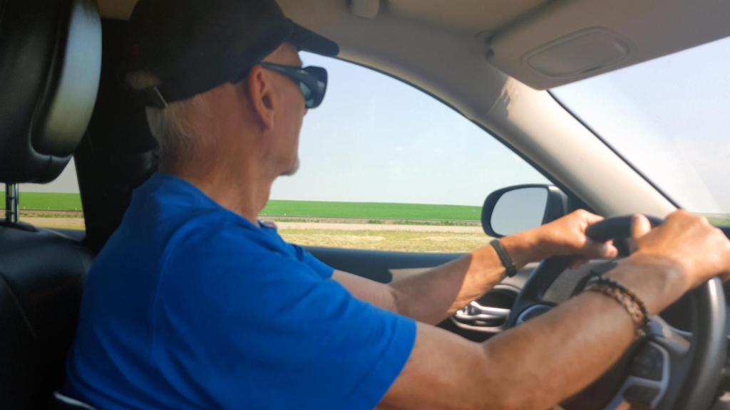 Un señor conduciendo con gorra.