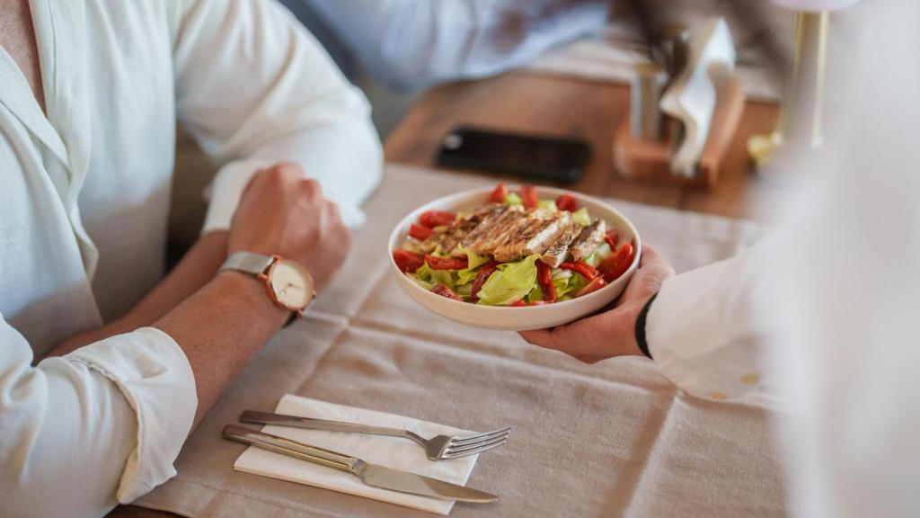 Un camarero sirve un plato a un cliente en un restaurante.