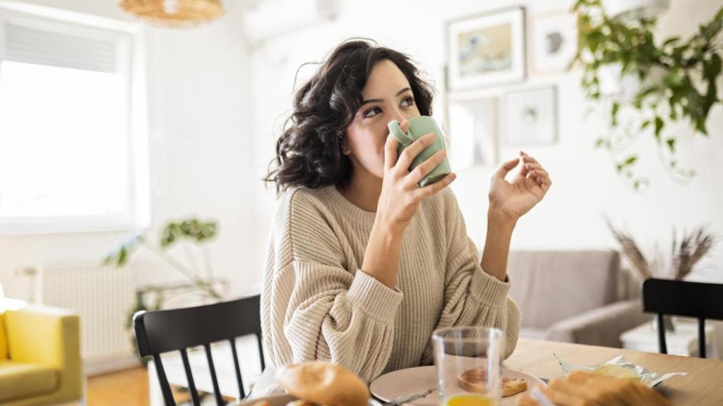 Mujer desayunando en su casa.