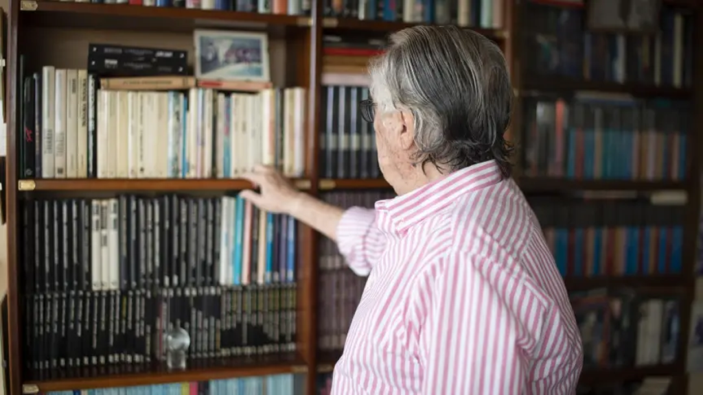 Vázquez-Figueroa observa los libros de la biblioteca de su casa.