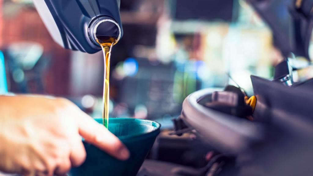 Un mecánico vierte aceite en el motor de un coche