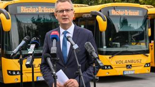 Hungarian Secretary of State Bence Rétvári poses next to the buses he intends to send to Brussels loaded with migrants