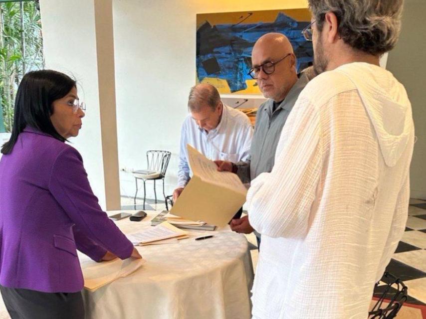 De izquierda a derecha: Delcy Rodríguez, Edmundo González (sentado), Jorge Rodríguez (de pie, con gafas) y el embajador español, Ramón Santos (de espaldas), en la sede diplomática española en Caracas.