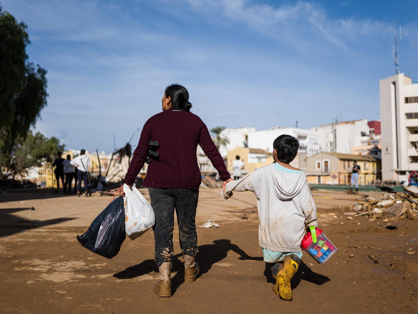 Una madre junto a su hijo abandona Paiporta con unos pocos enseres que han podido salvar de su casa