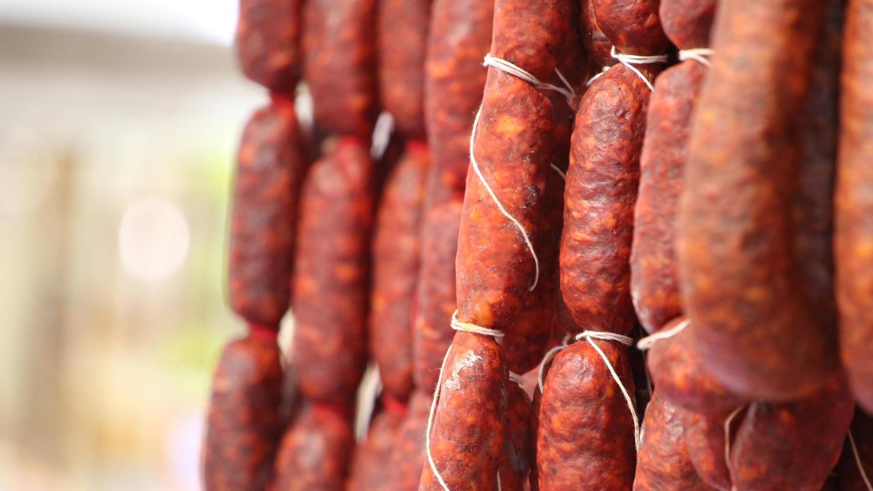 Primer plano de chorizos colgando en cuerdas.