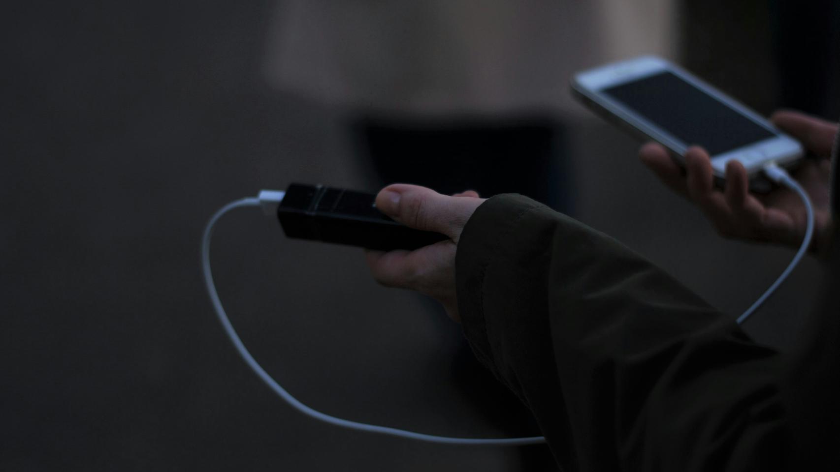 Una persona cargando el móvil con una batería portátil.