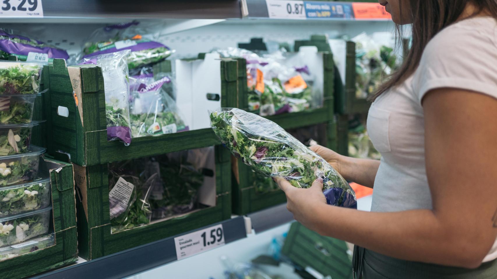 Imagen de archivo de una mujer comprando lechuga en un supermercado.