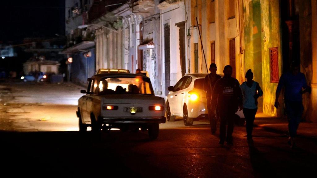 Un grupo de personas camina por una calle  sin servicio eléctrico en La Habana (Cuba).