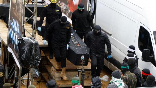 MIlicianos de Hamás con uno de los cadáveres entregados a Israel.