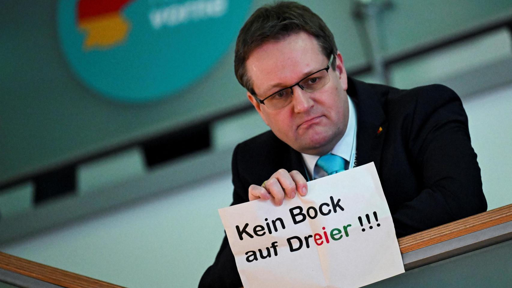 Una persona sostiene un cartel que dice: No hay deseo de tríos en la sede del partido Unión Demócrata Cristiana (CDU).