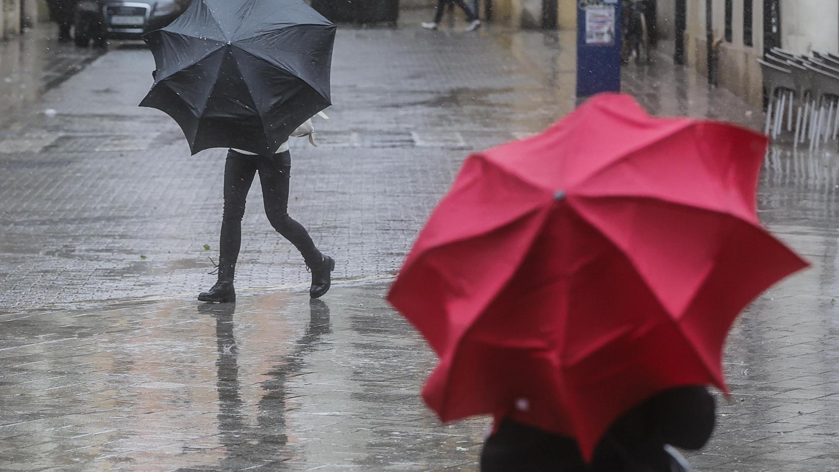 Dos personas sostienen paraguas como consecuencia de la lluvia, imagen de archivo. Europa Press / Rober Solsona