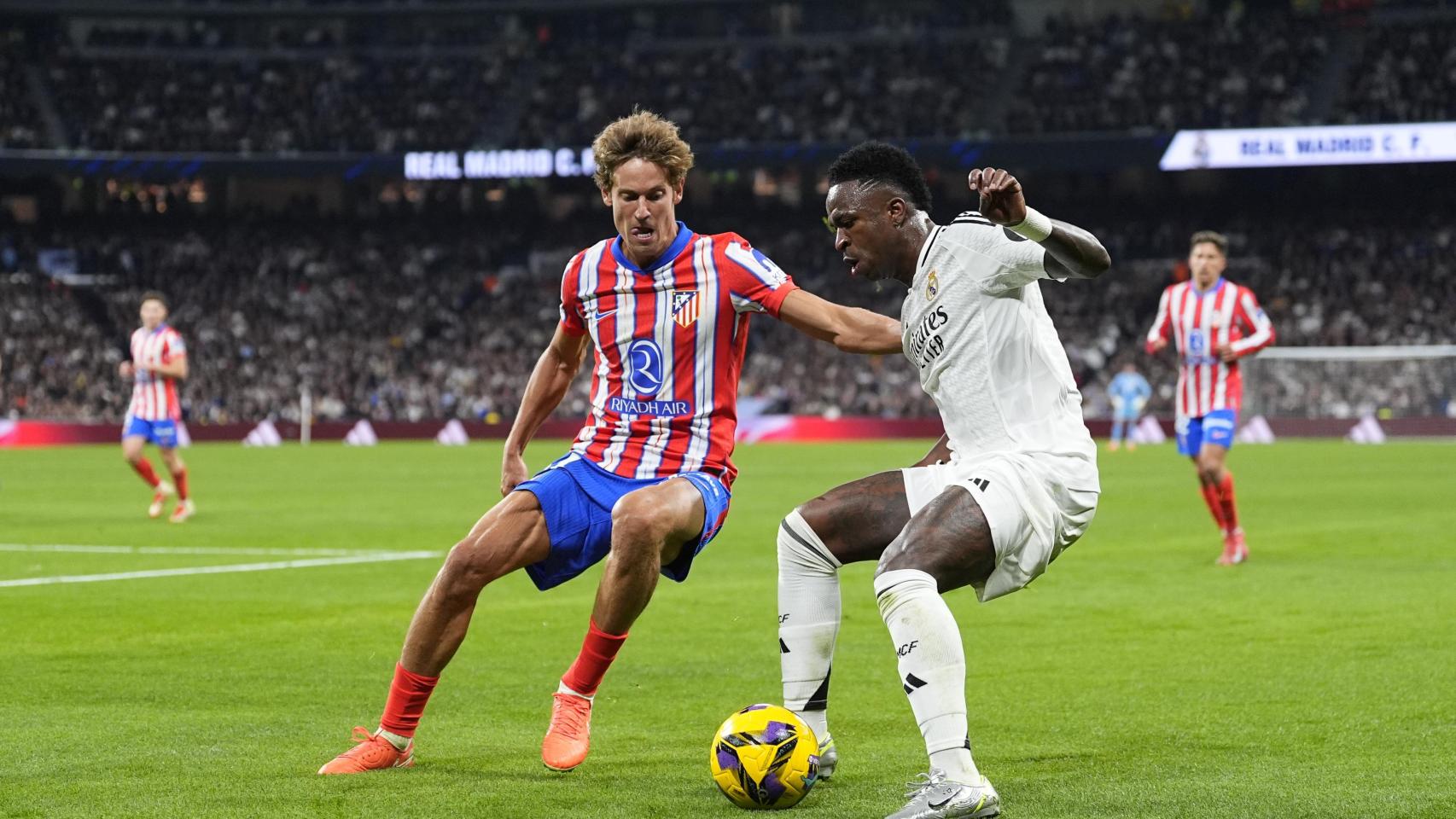 Vinicius contra Marcos Llorente durante un derbi entre Real Madrid y Atlético