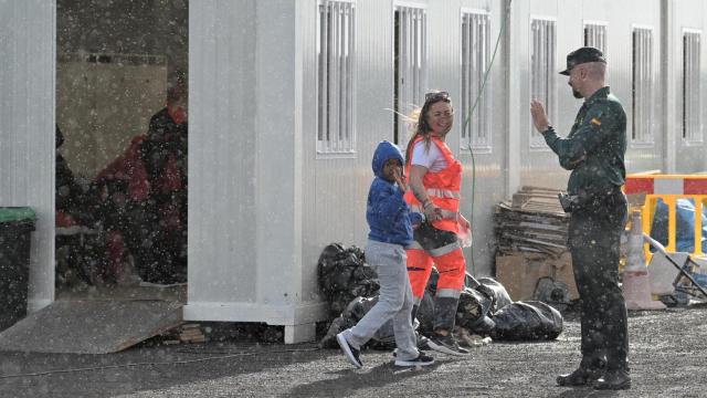 Un guardia civil saluda a menor llegado al puerto de La Restinga (El Hierro), tras el rescate de una patera con 45 ocupantes.