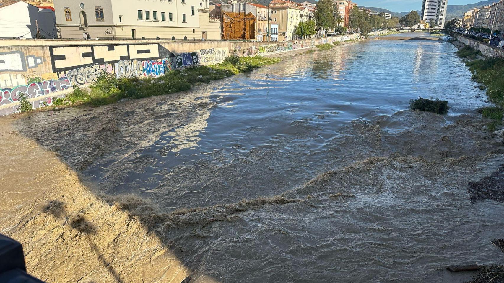 Imagen del río Guadalmedina con agua y, al fondo, las torres de Martiricos.