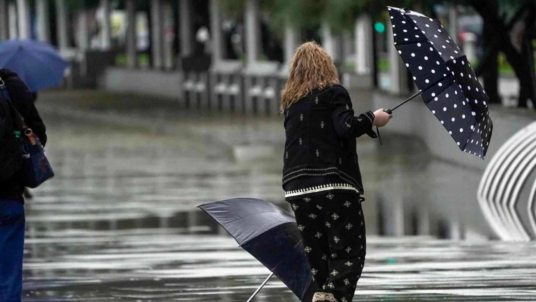 Una mujer intenta luchar contra la lluvia y el viento durante un temporal. (Archivo)