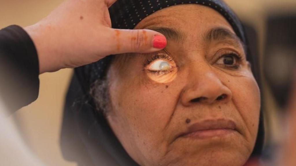 Mujer siendo graduada por las voluntarias, utilizando la luz para detectar los posibles problemas.