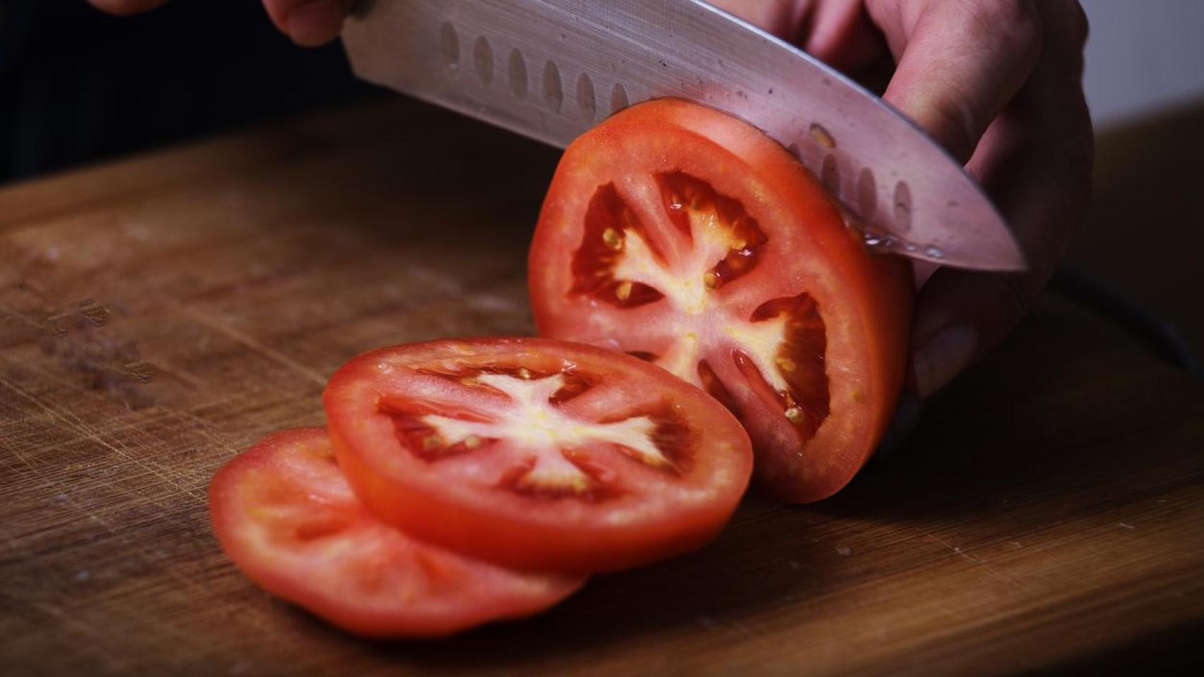 Tomate cortado en rodajas con un cuchillo afilado.