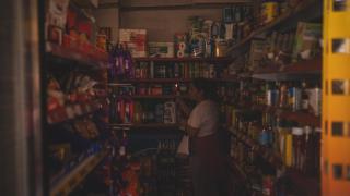 Una mujer haciendo la compra a oscuras a primera hora de la tarde del pasado lunes.