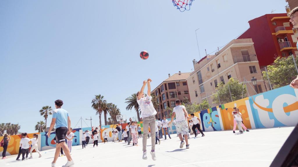 Los alumnos del centro juegan al baloncesto tras inaugurar la nueva pista de baloncesto.