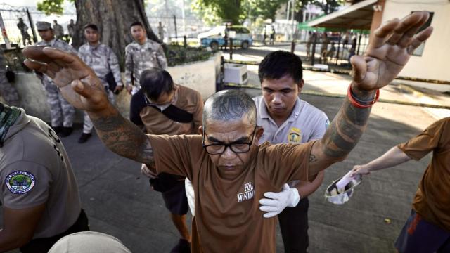 Un funcionario de prisiones revisa a un recluso filipino antes de que emita su voto en la Prisión Nacional Bilibid en Muntinlupa.