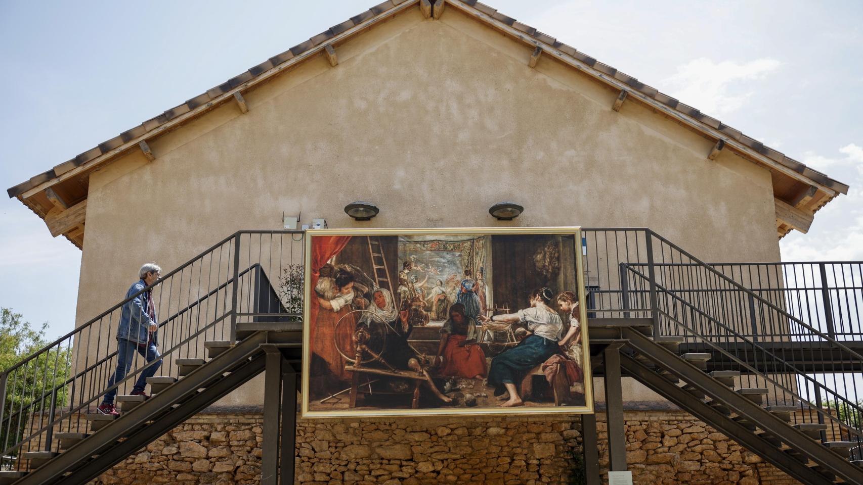 Una persona pasa ante el cuadro de Diego Velázquez Las hilanderas o La fábula de Aracne en una de las poblaciones afectadas por la dana. Efe / Biel Aliño