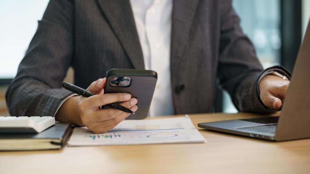 Imagen de archivo de una empleada en una oficina atendiendo a su móvil.
