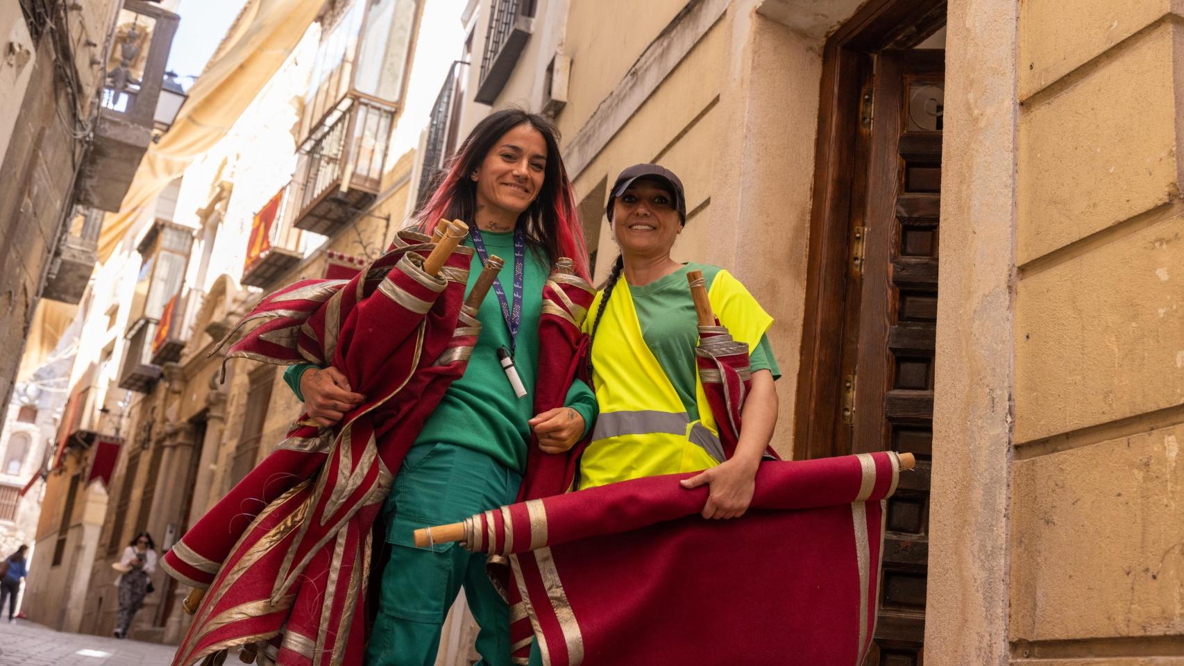 Dos operarias sujetan varios adornos con los que se engalanará el Corpus de Toledo.