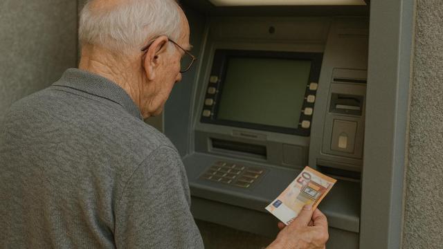 Un pensionista saca dinero de un cajero.