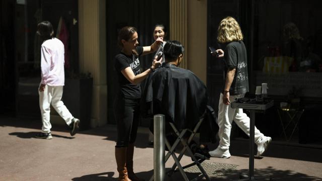 Una peluquera corta el pelo a una clienta en la calle debido a la falta de luz en su peluquería en Cannes.