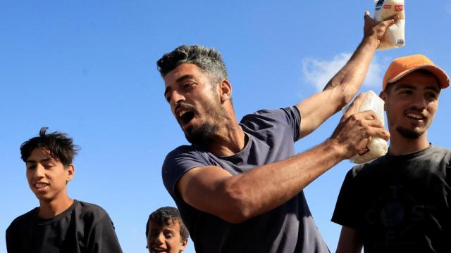 Una persona sostiene alimentos mientras los palestinos se reúnen cerca de un centro de distribución de ayuda dirigido por la Fundación Humanitaria de Gaza en el sur de la Franja de Gaza, el 27 de mayo de 2025.