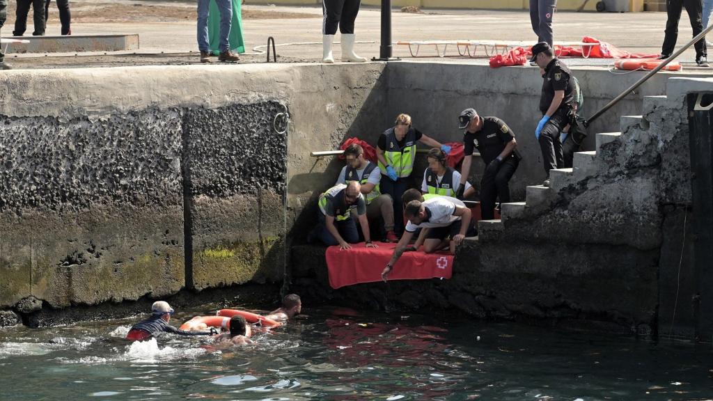 Agentes de Policía Nacional rescatan a uno de los migrantes que viajaba en el cayuco que ha volcado en su llegada al puerto de La Restinga.