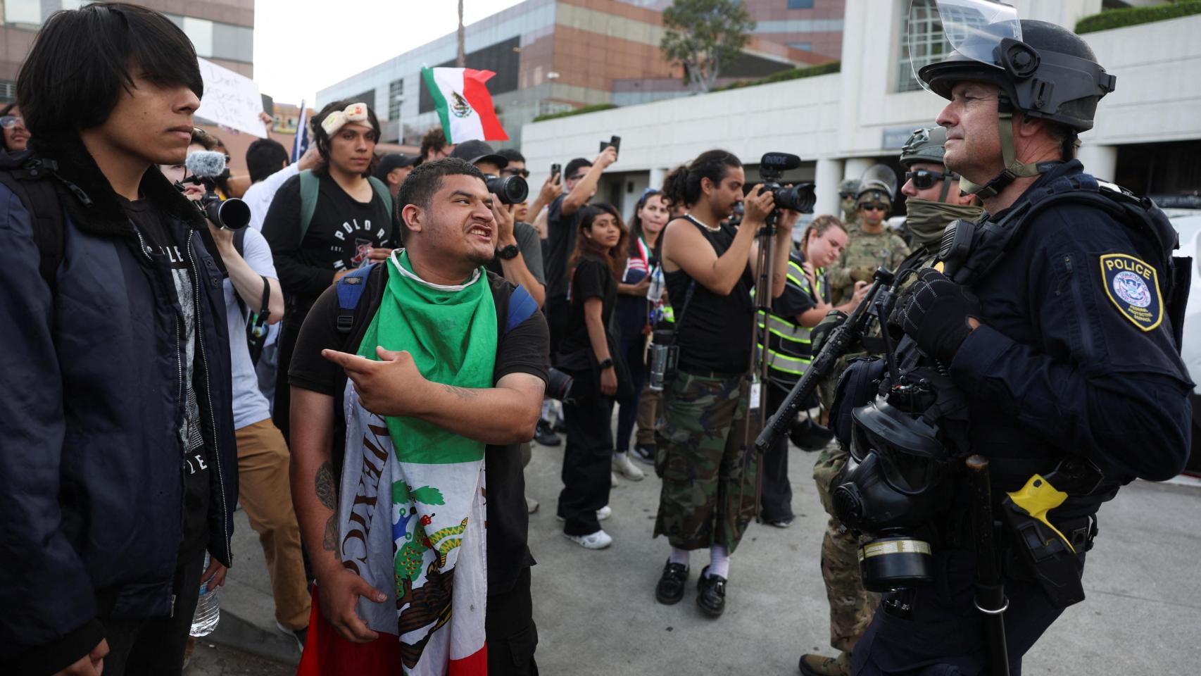 Un manifestante hace un gesto mientras agentes del orden hacen guardia cerca del edificio federal Edward R. Roybal, mientras continúan las protestas contra las redadas federales de inmigración en Los Ángeles, California, EEUU.