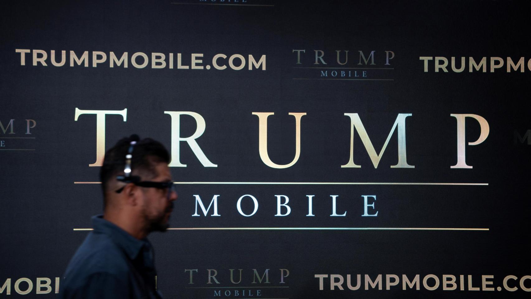 Un hombre pasa por delante de un cartel de Trump Mobile.