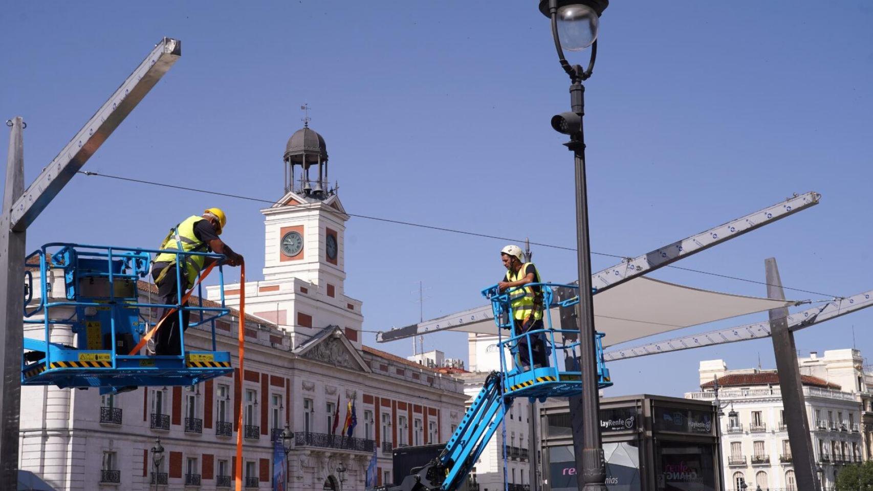 Dos operarios durante la instalación de los nuevos toldos de la Puerta del Sol.