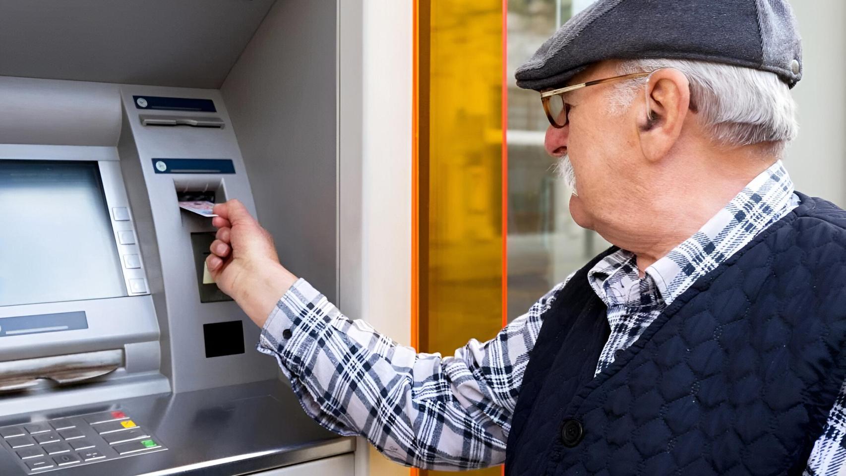 Un jubilado extrayendo dinero de un cajero, en imagen de archivo.
