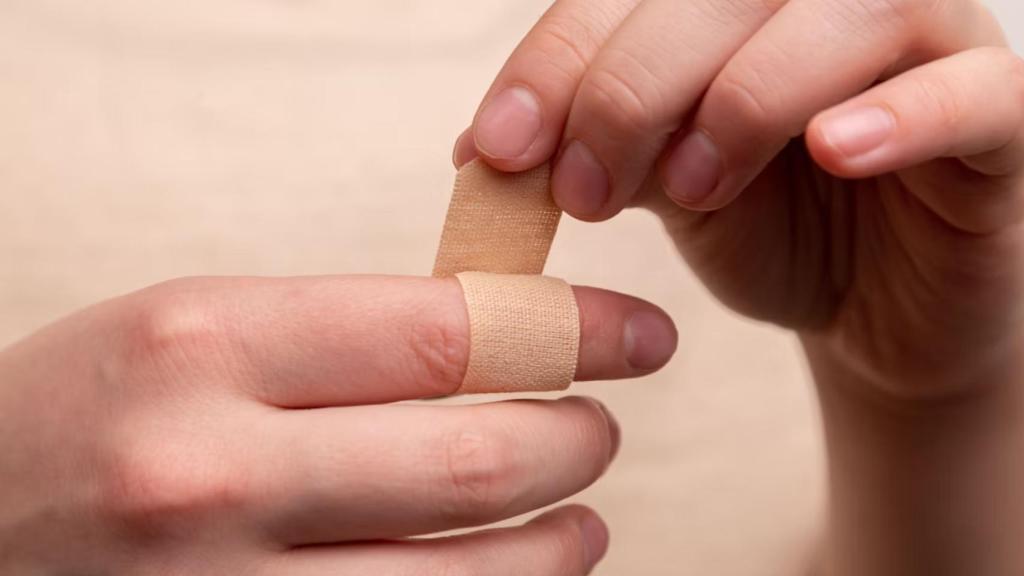 Una persona poniéndose una tirita en una herida en el dedo.