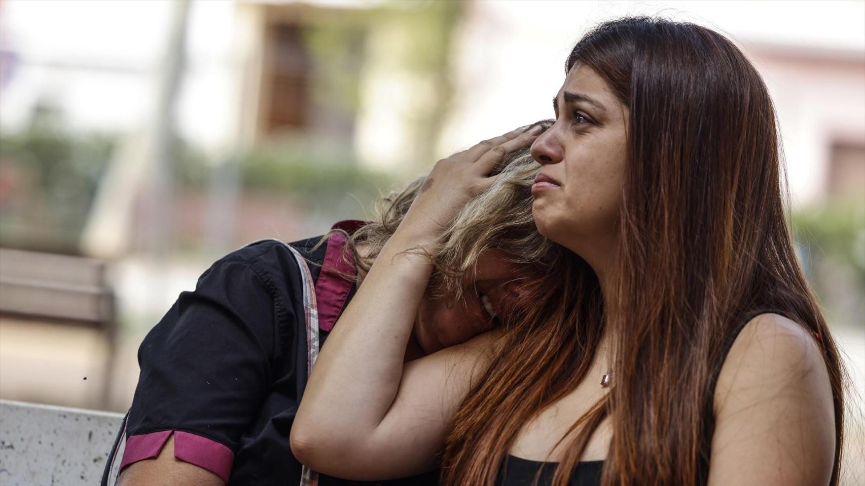 Dos personas se abrazan en el lugar de los hechos.