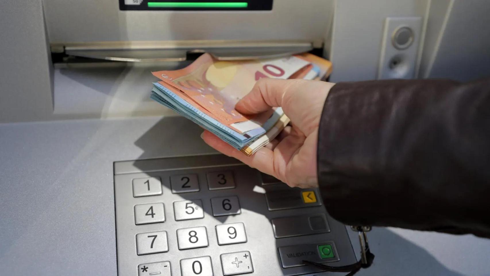 Una mujer saca dinero en un cajero automático.