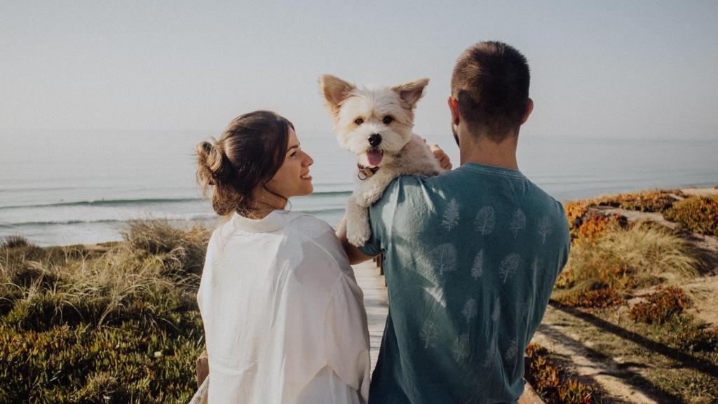Una pareja con su mascota en la playa.